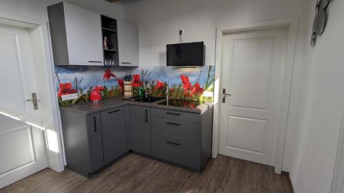 a kitchen with a sink with red flowers in it at Ferienwohnung im Kontor Penzlin in Penzlin