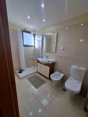 a white bathroom with a toilet and a sink at Cozy and Bright Apartment in Machico