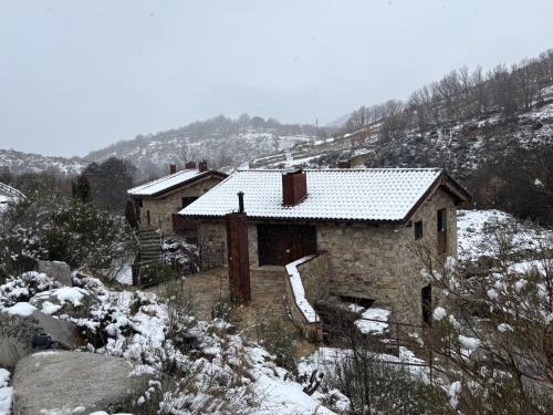 a house covered in snow on a snowy hill at Hotel Gredos María Justina in Navacepeda de Tormes