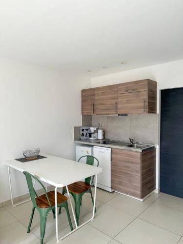 une cuisine avec une table blanche, des chaises et un comptoir dans l'établissement Petit Cocon - Parking - Climatisation - Wifi, à Cassis