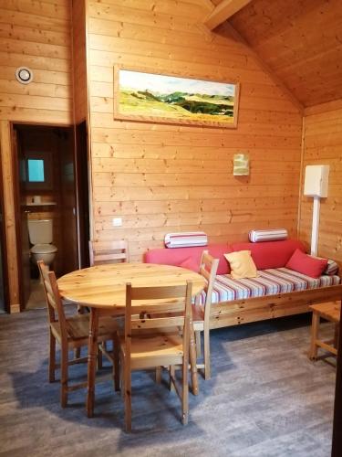 Cette chambre comprend un canapé, une table et des chaises. dans l'établissement Le Chalet de Lilie, à Bassignac