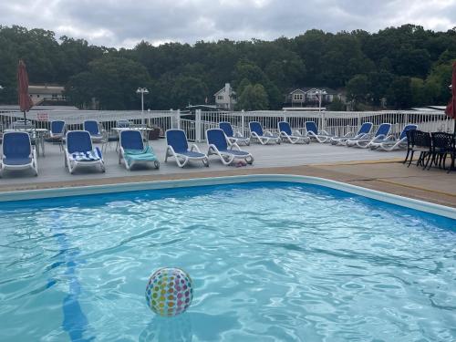 a swimming pool with chairs and a ball in the water at STAIRS OPTIONAL! Lakefront! Pool! On Water! Convenient Fishing! in Osage Beach