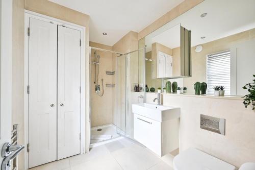 a white bathroom with a sink and a mirror at Spacious Fitzrovia Apartment 3 Bed in London