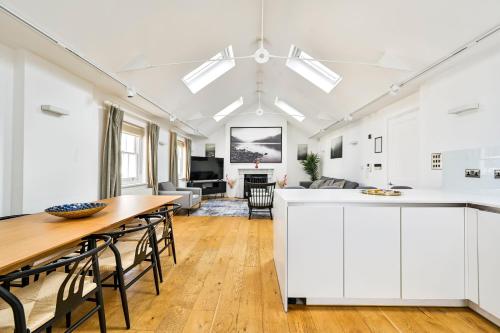 a kitchen and living room with white cabinets and a wooden table at Spacious Fitzrovia Apartment 3 Bed in London