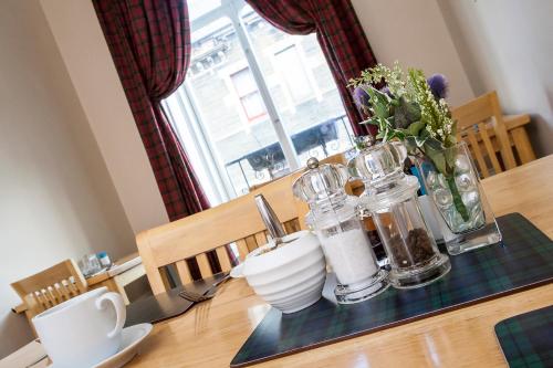 una mesa con un jarrón de flores y jarras. en Bank Guest House, en Wick