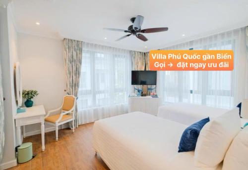 Un dormitorio con una cama blanca y un ventilador de techo. en Villa Phú Quốc Gần Biển, en Phu Quoc