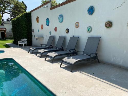 a group of chairs sitting next to a wall next to a swimming pool at Paradise Villa in Cocoyoc in Cocoyoc