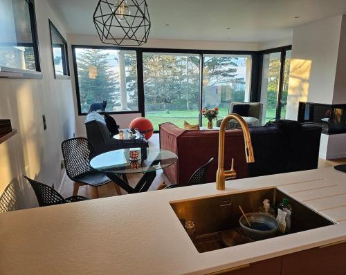 une cuisine avec un évier et un salon dans l'établissement Votre parenthèse enchantée dans Ty Nids d'Amour, à Névez