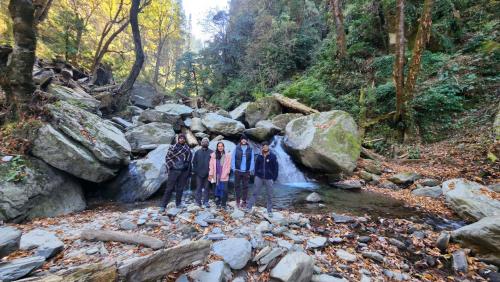 a group of people standing in a stream at Ailyak Stays and Cafe, Shoja, Jibhi in Shoja