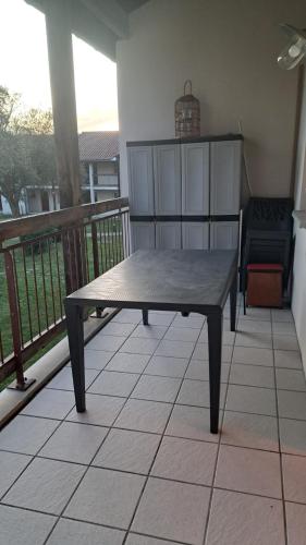 a wooden table on a balcony with a bench at L'airial de Laure in Ondres