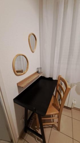 a black table with a chair and two mirrors at L'airial de Laure in Ondres