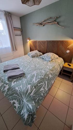 a bedroom with a bed with a green and white comforter at L'airial de Laure in Ondres