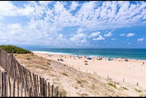 a beach with a fence and a crowd of people at L'airial de Laure in Ondres