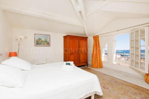 une chambre avec un lit blanc et une grande fenêtre dans l'établissement Le Clos d'Azur, à Cannes
