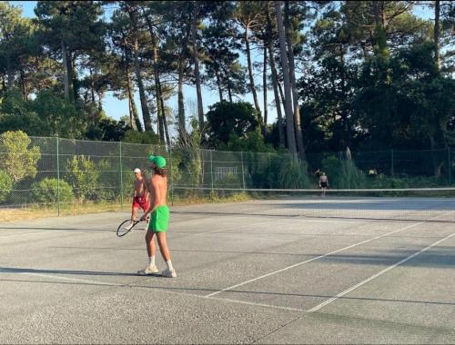 two women playing tennis on a tennis court at L'airial de Laure in Ondres