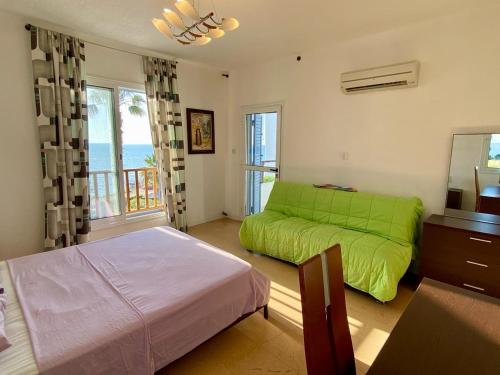 a bedroom with a green bed and a couch at Sea Front Villa Ekaterina in Paphos City