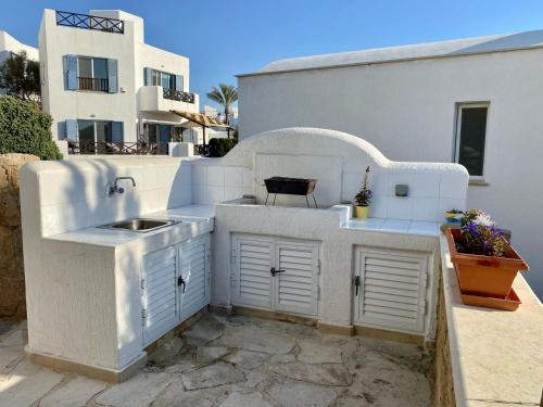 a white outdoor kitchen with a sink and a building at Sea Front Villa Ekaterina in Paphos City
