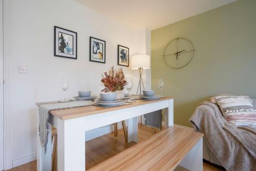 a living room with a table and a clock on the wall at Charming House - Close to Shops & City Centre - Free Parking, Self-Check-In, Fast WiFi & Smart TV with Netflix by Yoko Property in Milton Keynes