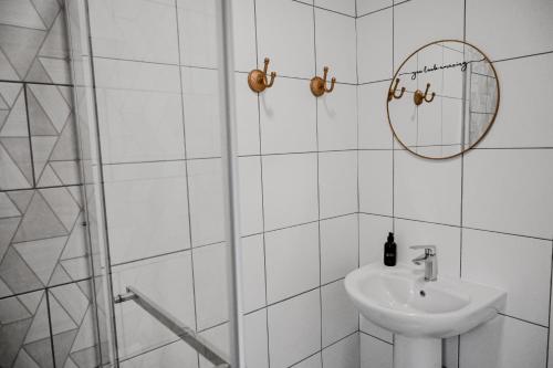 a white bathroom with a sink and a mirror at Reveuse in Pretoria
