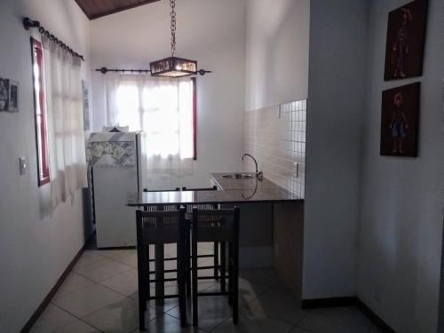 a kitchen with a counter and a refrigerator and chairs at Pousada Aquarela Pipa in Pipa