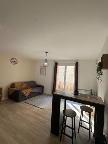 a living room with a table and two stools in it at Charmant studio in Courseulles-sur-Mer