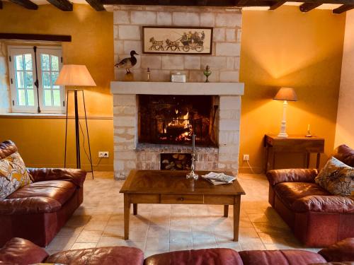 un salon avec des canapés et une cheminée dans l'établissement L'Allée - Maison d'hôtes - Charme - Digital detox, à Vernantes