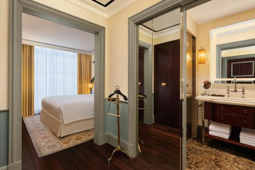 a bedroom with a bed and a bathroom with a sink at Maxwell Reserve Singapore, Autograph Collection in Singapore