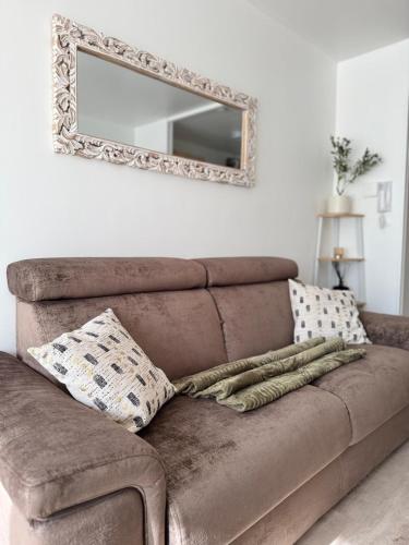 a brown couch in a living room with a mirror at Le Colisée à deux pas in Mainvilliers