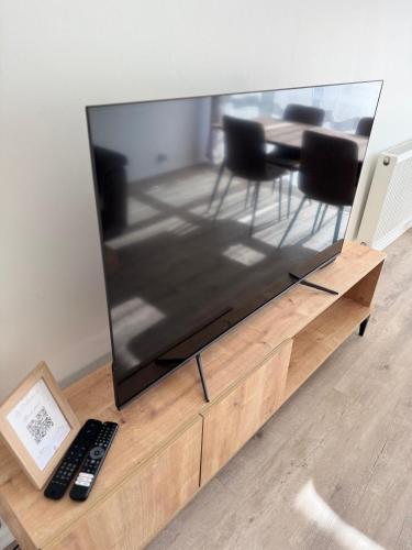 a large flat screen tv sitting on a wooden entertainment center at Le Colisée à deux pas in Mainvilliers