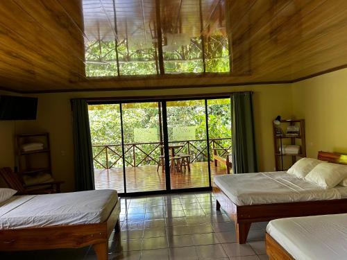 a bedroom with two beds and a large window at Vista Drake Lodge in Drake Bay Airport