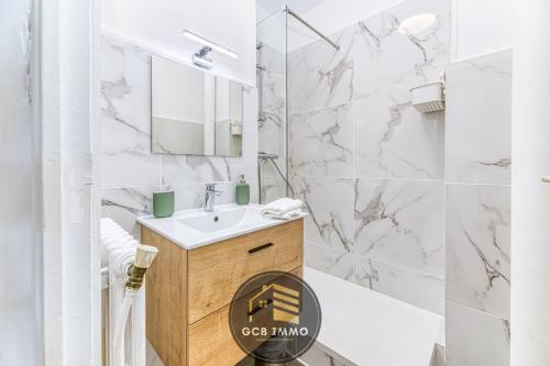 une salle de bain blanche avec un lavabo et un miroir dans l'établissement Le Balzac - T2 Cosy proche centre ville - Stationnement gratuit, à Grenoble