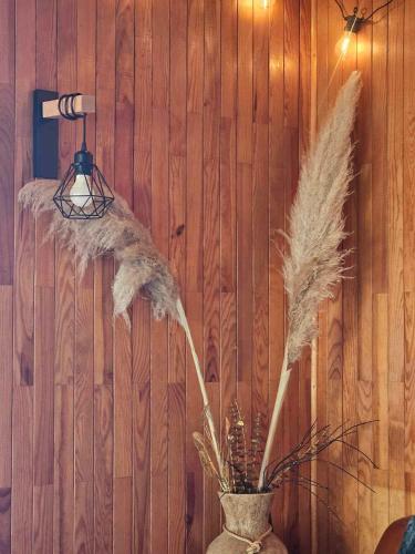 a vase with feathers in front of a wooden wall at Le chalet des Ecureuils - Vue imprenable sur la Dent du Chat in Saint-Jean-de-Chevelu