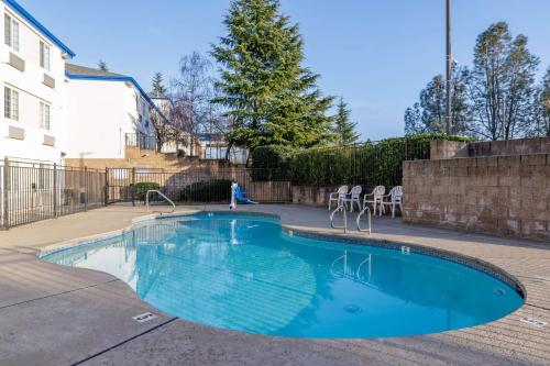 a swimming pool in a courtyard with chairs around it at Motel 6-Auburn, CA in Auburn