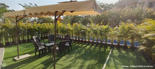 a patio with a table and chairs under an umbrella at Sa-Rang! Where Love Blossoms Karjat in Karjat