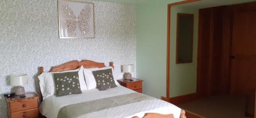 a bedroom with a bed with two night stands and two lamps at Henblas Holiday Cottages in Abergele