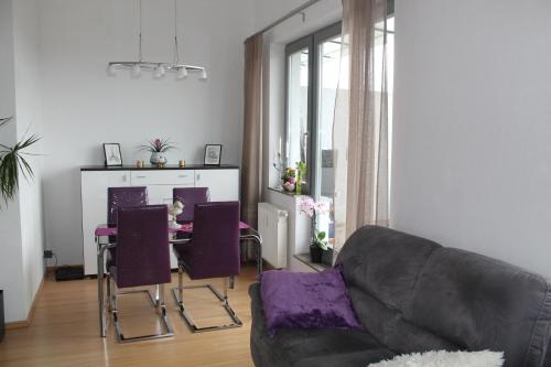 a living room with a couch and a table with purple chairs at BS Business Travelling Hannover City in Hannover