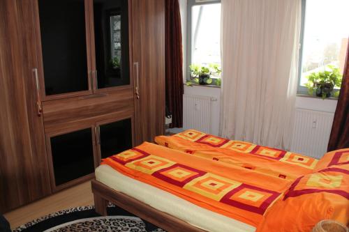 a bedroom with a bed with an orange comforter at BS Business Travelling Hannover City in Hannover