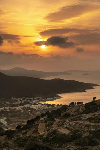 a sunset over a city and a body of water at mikro.kastro kalotaritissa in Chora Amorgos in Amorgos