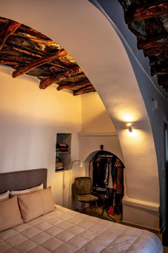 a bedroom with a bed and a chair in a room at mikro.kastro kalotaritissa in Chora Amorgos in Amorgos