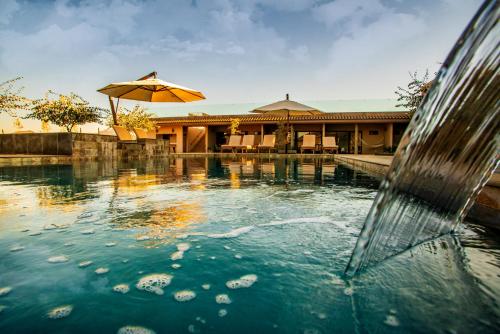 a pool of water with an umbrella in front of a building at Hotel Flores de Sal-Valle de Guadalupe in Valle de Guadalupe