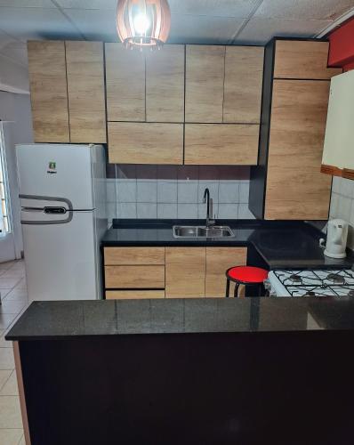a kitchen with a white refrigerator and wooden cabinets at Departamento in Comodoro Rivadavia