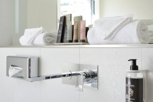 a bathroom with a towel dispenser on a shelf at SeminarHotel am Ägerisee in Unterägeri