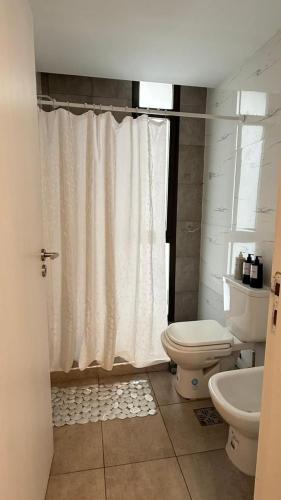 a bathroom with a toilet and a shower curtain at Carlos Paz-Lake Towers in Villa Carlos Paz