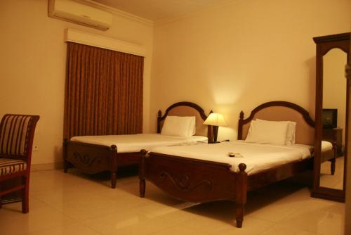 a bedroom with two beds and a chair at Hotel Ornate in Dhaka