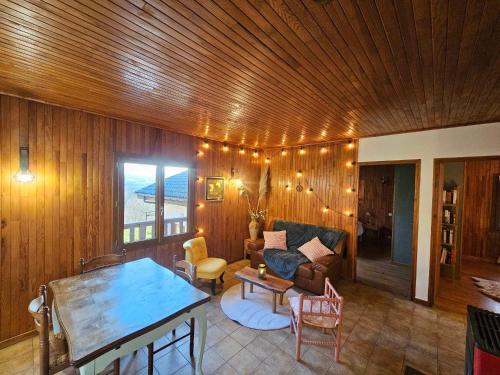 a living room with a couch and a table at Le chalet des Ecureuils - Vue imprenable sur la Dent du Chat in Saint-Jean-de-Chevelu