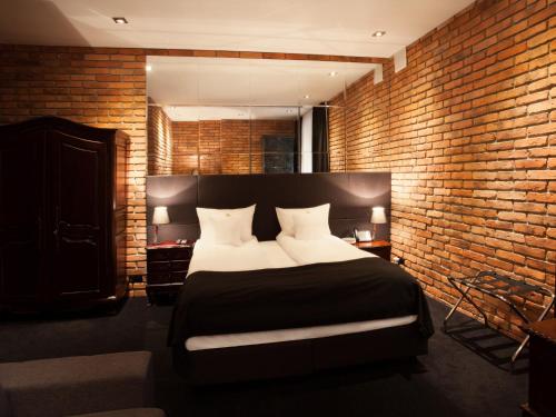 a bedroom with a large bed with a brick wall at Hotel Betmanowska Main Square Residence Adults Only in Kraków
