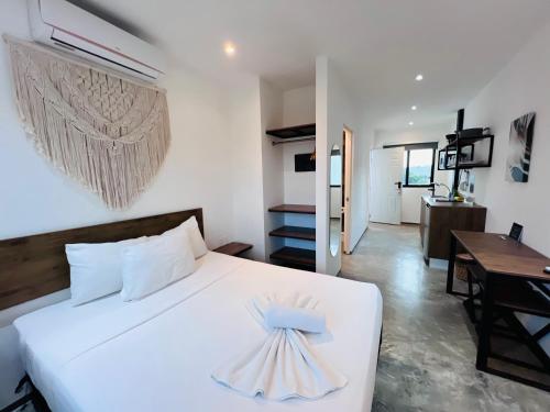 a bedroom with a white bed with a dress on it at Coco Live Suites in Playa del Carmen