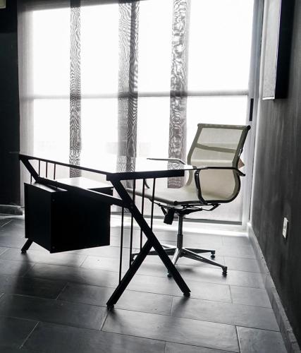 a desk and a chair in a room with a window at Spacious Black Themed Apartment Victoria Island in Lagos