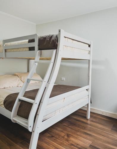 a white bunk bed in a room with a ladder at Departamentos Santa Bárbara Osorno in Osorno