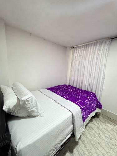 a small bedroom with a bed with a purple blanket at Apartamento Edificio Parques Del Trianon in Envigado